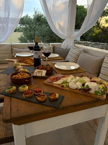 Tavola salentina al tramonto con vino rosso e antipasti